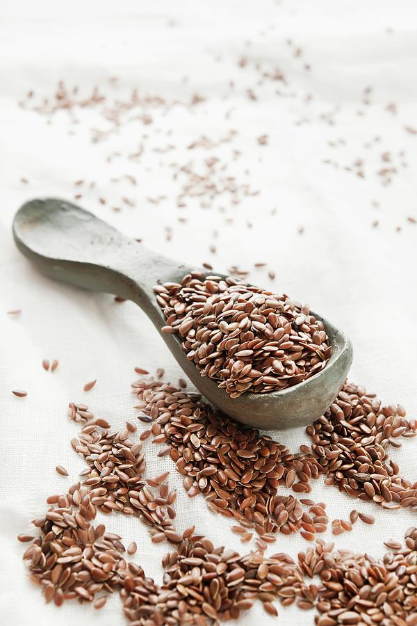 Flax Seeds On A Wooden Spoon And On A White Tablecloth Photograph by Atelier Hmmerle