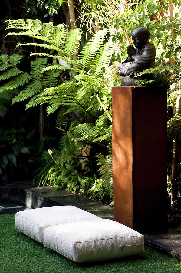 Floor Cushions On Artificial Grass In Front Of Statue Of Buddha And Tall Ferns Photograph by Great Stock!