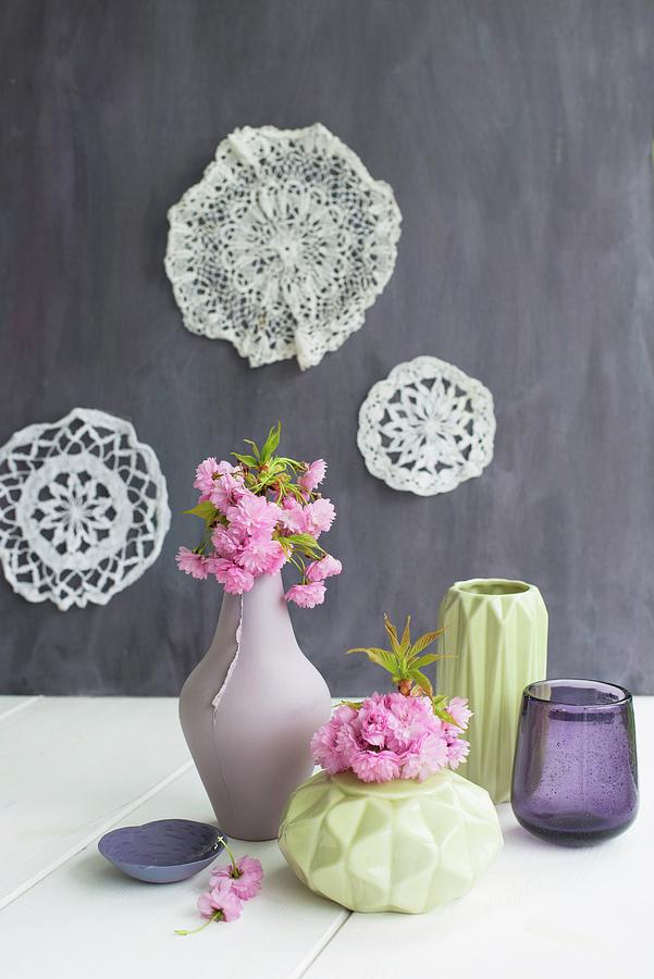 Flowering Branches In Vases With Structured Surfaces And Lace Doilies On Wall Photograph by Patsy&christian