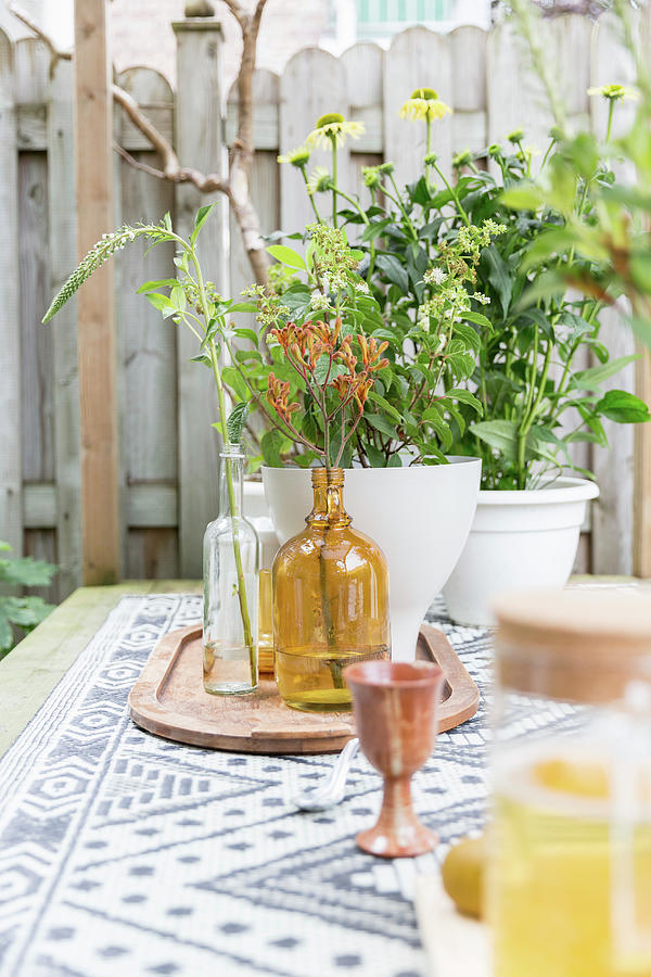Flowers And Vases In Shades Of Yellow And Brown On Table In Garden Photograph by Studio Lumino