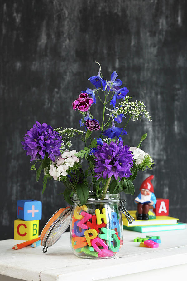 Flowers In Preserving Jar Of Water And Colourful Letters Photograph by Thordis Rggeberg