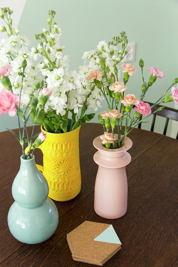 Flowers In Vases Of Various Colours And Cork Coasters Photograph by Ilaria Chiaratti