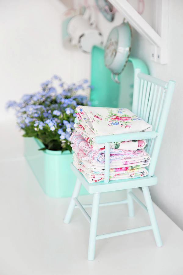 Folded Floral Fabrics On Mint-green Wooden Chair Photograph by Syl Loves