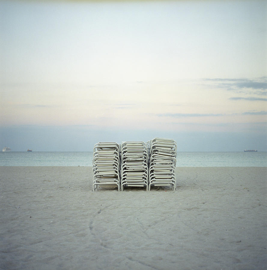 Folding Chairs Stacked On A Beach On Photograph by Peter Baker