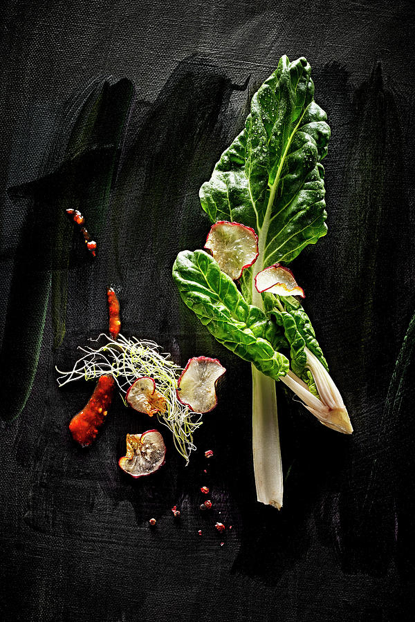 Food Art: Chard With Red Celery, Pink Pepper, Beansprouts And Chilli Sauce On A Black Surface Photograph by Manfred Rave