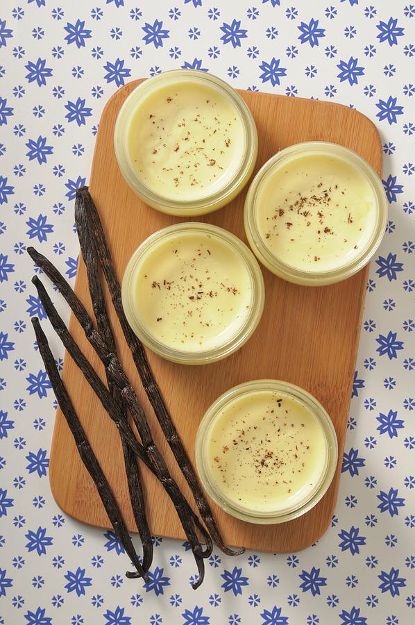 Four Dishes Of Vanilla Cream On A Wooden Board With Vanilla Pods Photograph by Jean-christophe Riou