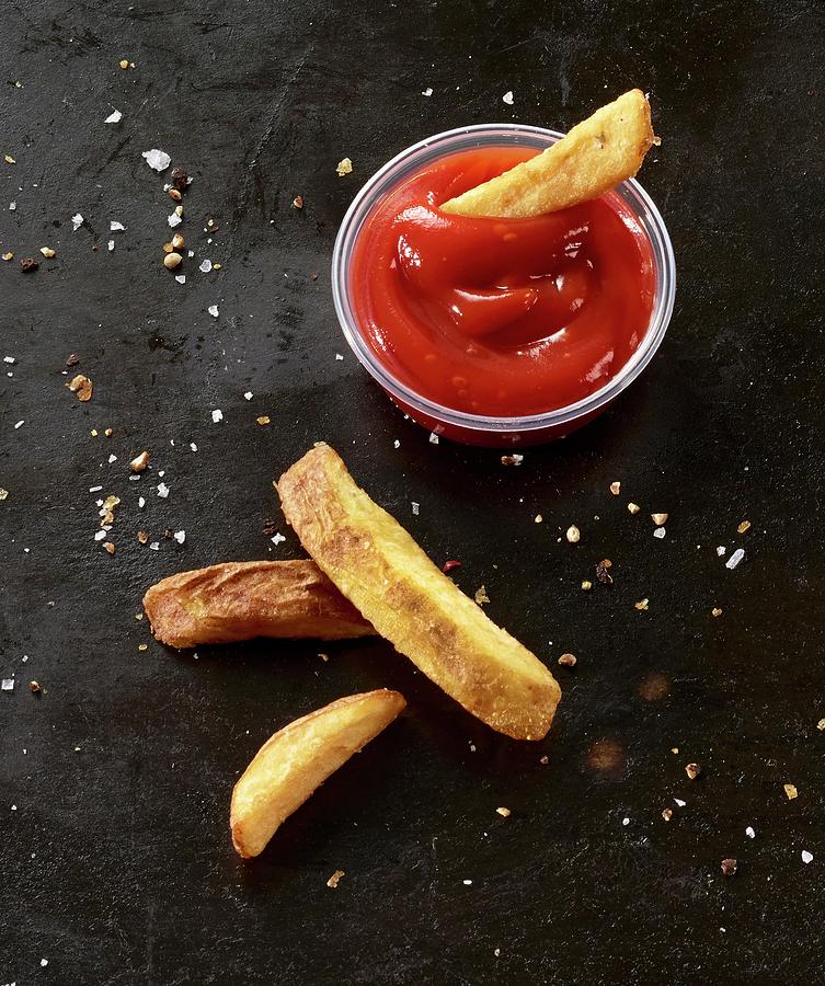 Four French Fries On A Black Baking Tray With Tomato Ketchup Photograph by Ludger Rose