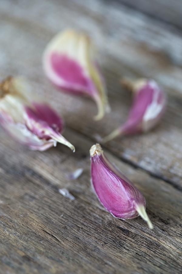 Four Garlic Cloves On A Wooden Surface close Up Photograph by Malgorzata Laniak