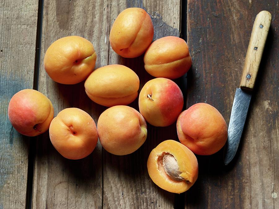 Fresh Apricots With A Kitchen Knife On A Wooden Surface Photograph by Brigitte Wegner