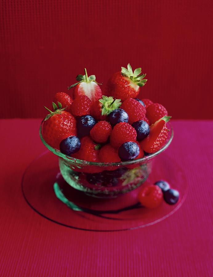 Fresh Berries In A Glass Bowl On A Pink Tablecloth Against A Red Background Photograph by Jonathan Gregson