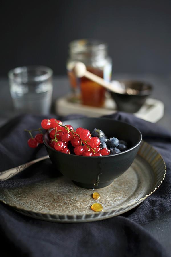 Fresh Berries With Honey In A Dark Bowl Photograph by Eva Lambooij