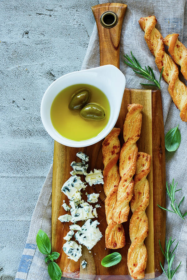 Fresh Blue Cheese With Olives, Basil, Rosemary And Grissini Bread Sticks On Wooden Serving Board Over Grey Concrete Textured Background Photograph by Yuliya Gontar
