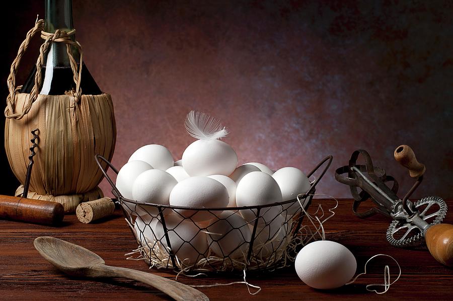 Fresh Eggs In A Wire Basket Next To Antique Kitchen Utensils And A Bottle Of Wine Photograph by Elio Lombardo