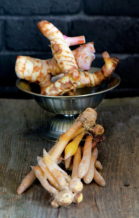 Fresh Galangal Roots In A Bowl With Fingerroots On A Wooden Board Photograph by Jamie Watson
