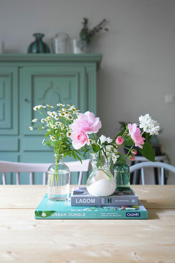 Fresh Garden Flowers In Three Small Vases And Books On Table Photograph by Ilaria Chiaratti
