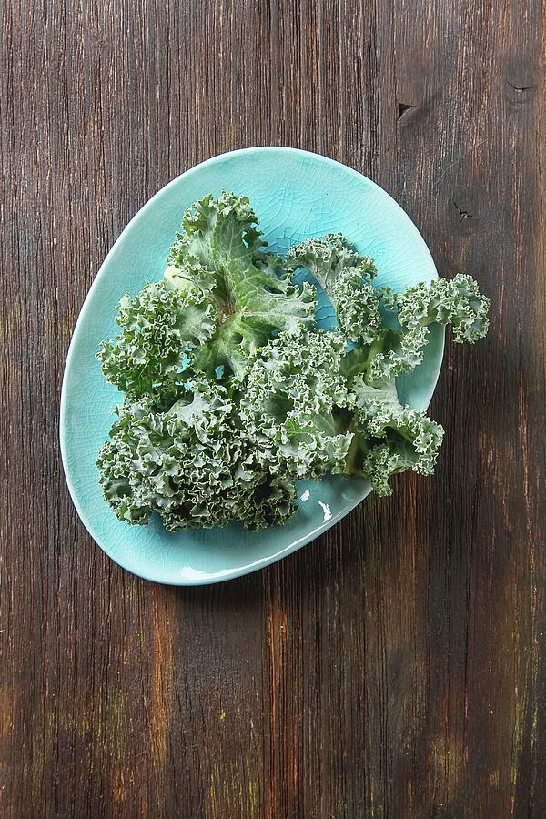 Fresh Kale Leaves On A Blue Plate On A Wooden Surface Photograph by Naltik