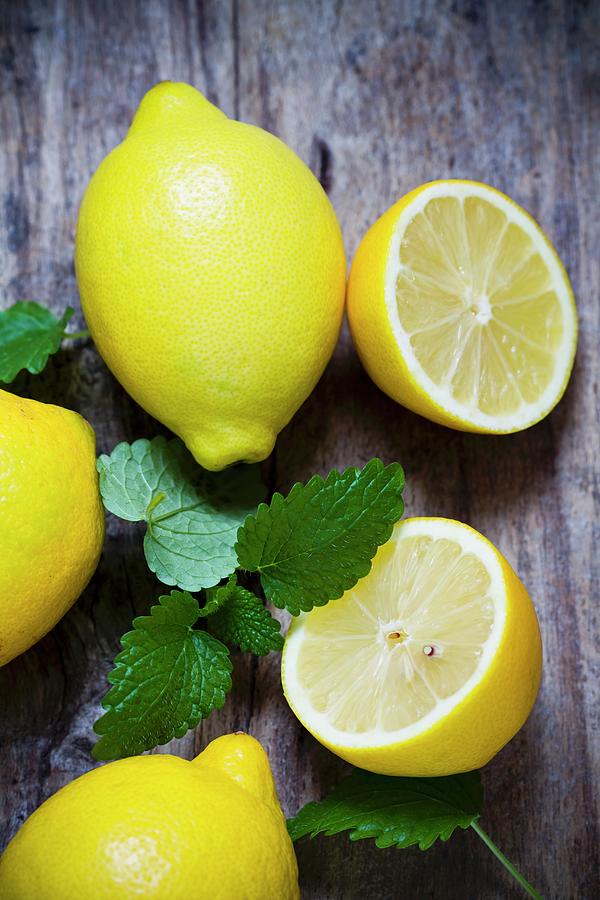 Fresh Lemons And Lemon Balm On A Wooden Surface Photograph by Sporrer/skowronek