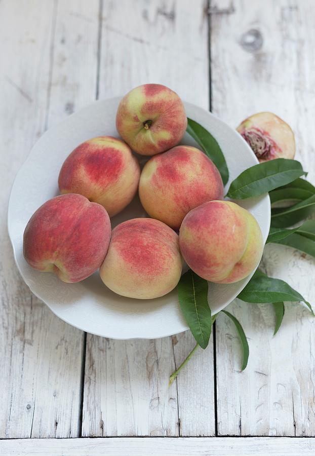 Fresh Peaches With Leaves On A Plate Photograph by Adel Bekefi