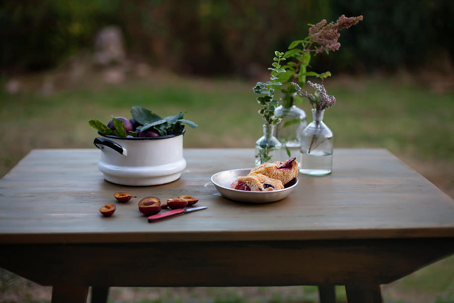 Fresh Plums In A Pot And Plum Cake In A Metal Bowl On A Garden Table Photograph by Alicja Koll