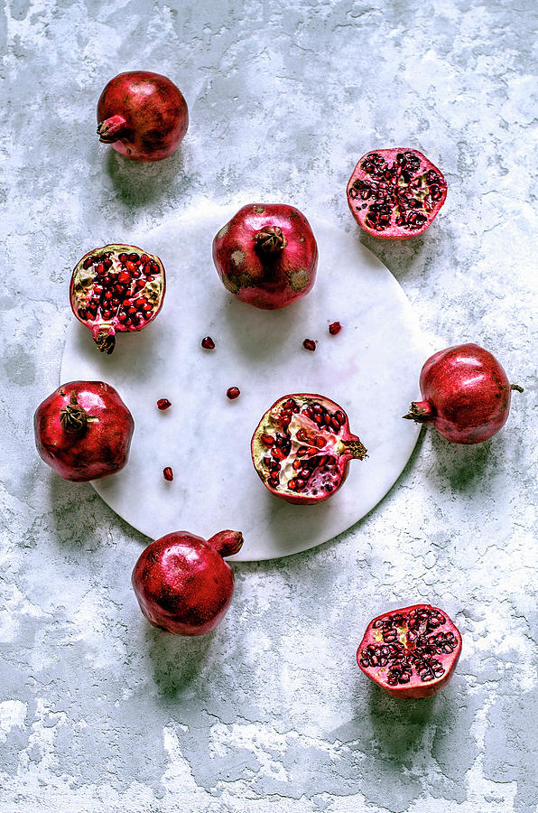 Fresh Pomegranates Whole And Cut With Scattered Grains On A Marble Tray Photograph by Gorobina