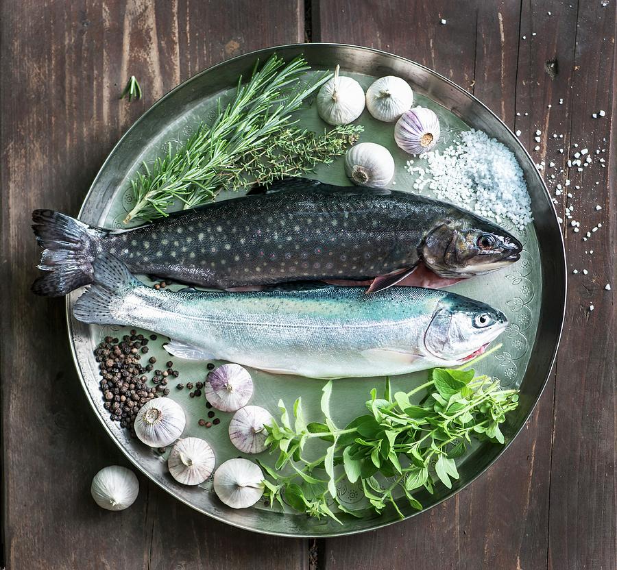 Fresh Rainbow Trout, Char, Garlic, Thyme, Salt, Pepper, Rosemary And Oregano On A Tray Photograph by Fotografie-lucie-eisenmann