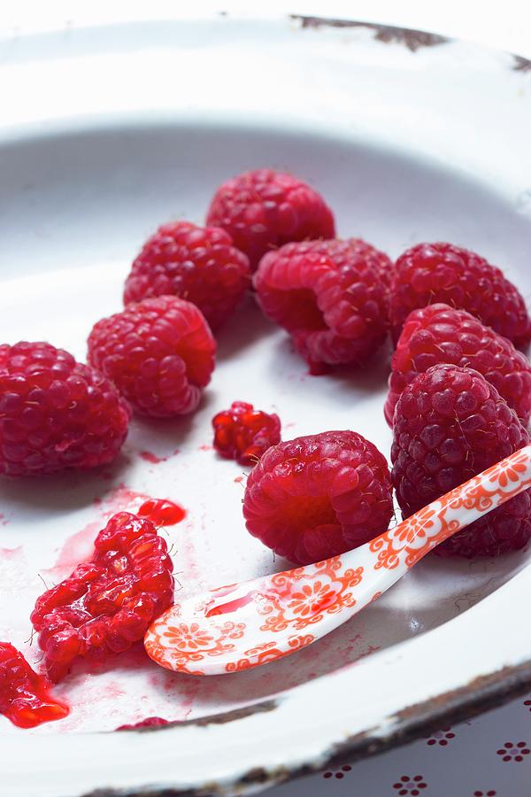 Fresh Raspberries On An Enamel Plate With A Porcelain Spoon Photograph by Charlotte Von Elm
