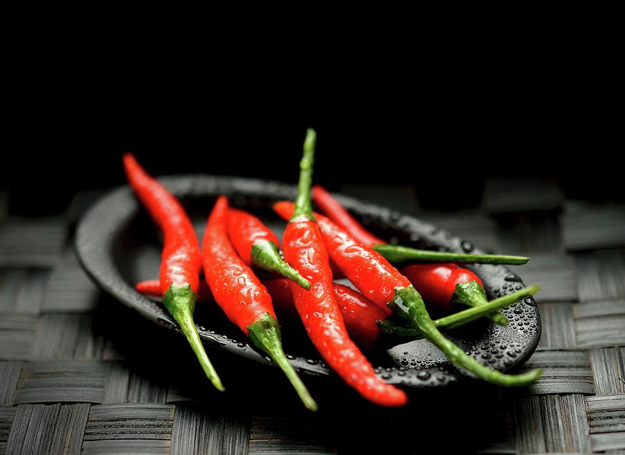 Fresh Red Chilli Peppers On A Black Plate Photograph by Kaktusfactory
