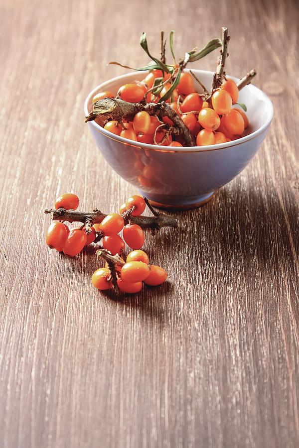 Fresh Sea Buckthorn In A Bowl And Next To It On A Wooden Surface Photograph by Naltik