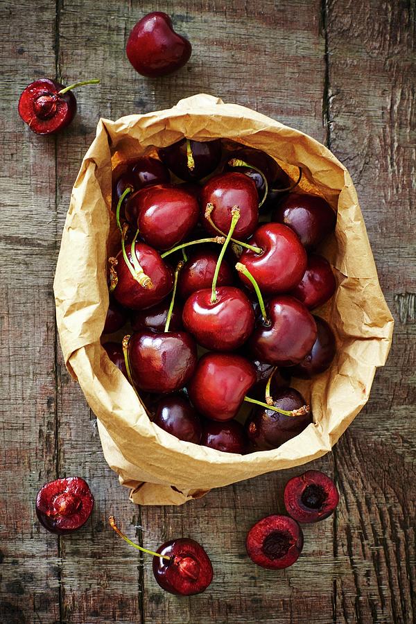 Fresh Spanish Cherries In A Brown Paper Bag On A Wooden Board Photograph by Tim Atkins Photography