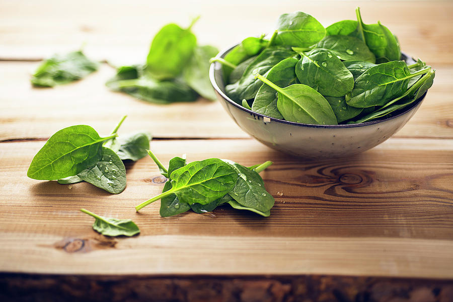 Fresh Spinach Leaves In A Bowl And On A Wooden Table Photograph by Jrg Strehlau