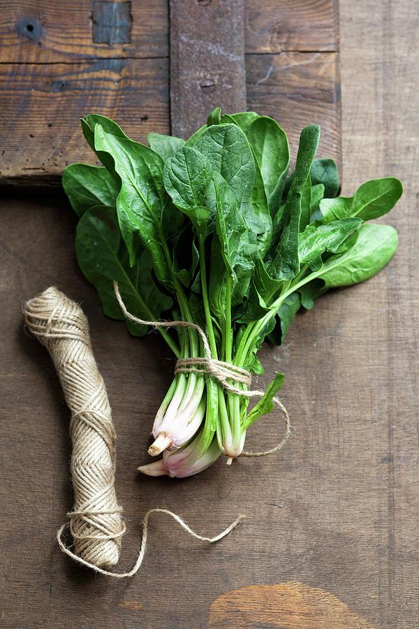 Fresh Spinach Leaves Tied With Kitchen Twine On A Wooden Surface Photograph by Victoria Firmston