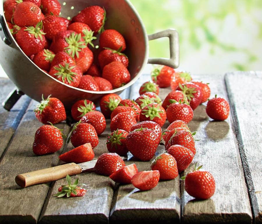 Fresh Strawberries In A Colander And On A Wooden Table, Some Sliced Photograph by Ludger Rose