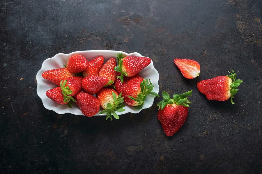 Fresh Strawberries In A White Dish On A Black Metal Surface Photograph by Christoph Maria Hnting