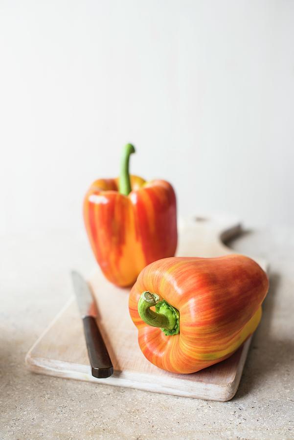 Fresh Striped Red Peppers On A Chopping Board With A Knife Photograph by Magdalena Hendey