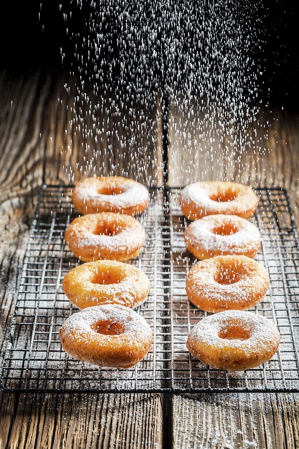 Freshly Baked Doughnuts Being Dusted With Icing Sugar Photograph by Shaiith