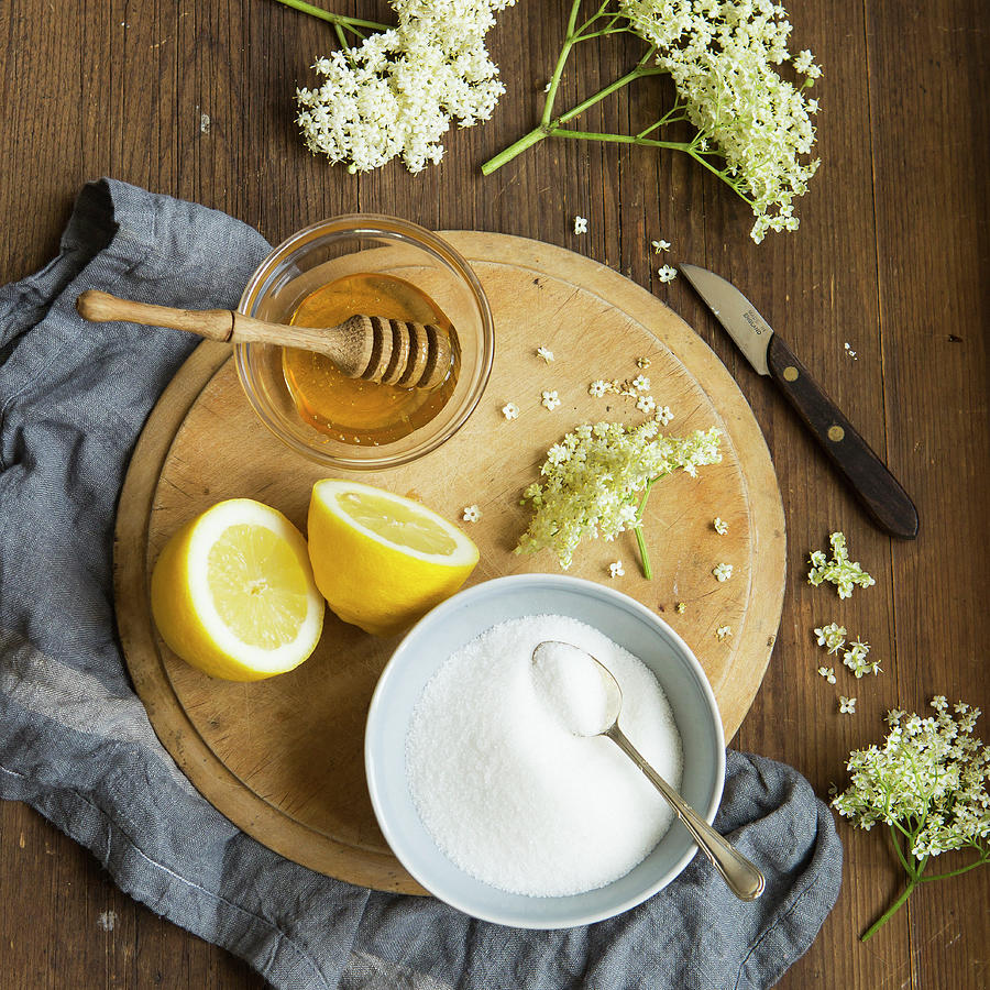 Freshly Picked Elderflowers On And Around A Chopping Board Of The Ingredients That Go Into Making Elderflower Cordial, Lemons, Honey And Sugar Photograph by Stacy Grant