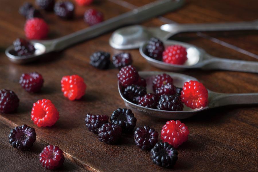 Freshly Picked Red And Black Wild Raspberries On Silver Spoons On A Wooden Surface Photograph by Katharine Pollak