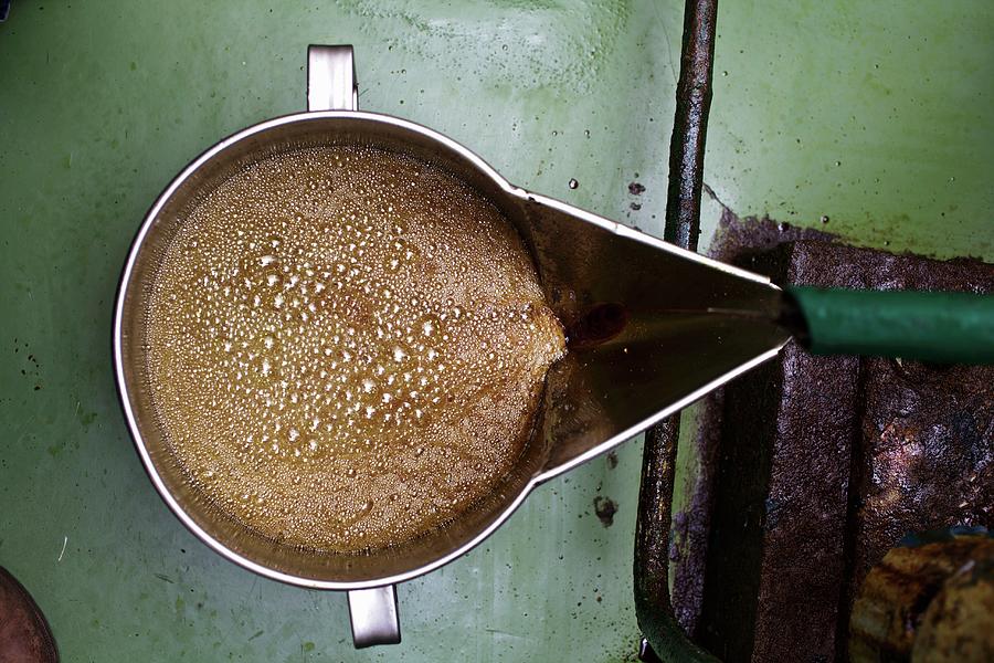 Freshly Pressed Pumpkin Seed Oil Flowing Into A Bucket Photograph by Herbert Lehmann