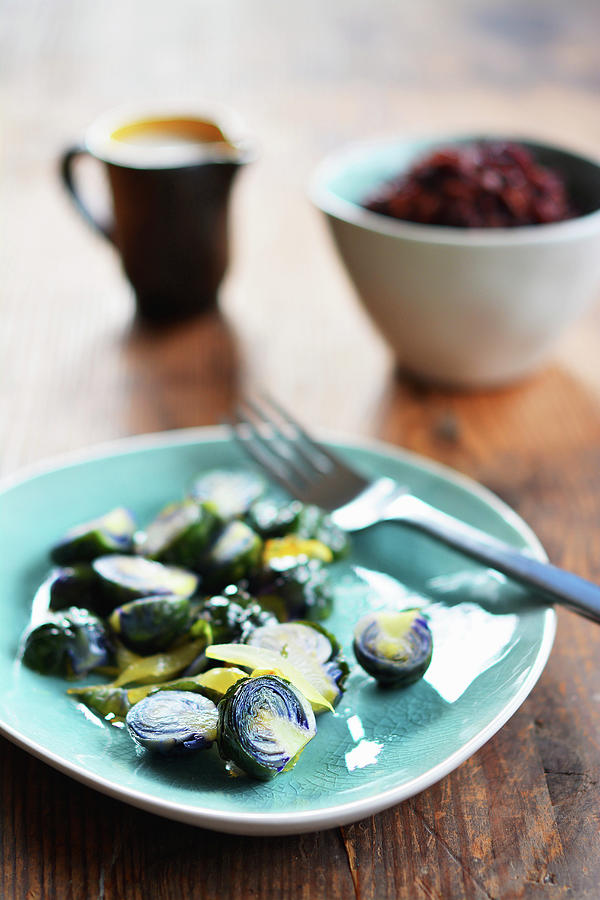 Fried Brussels Sprouts On A Ceramic Plate In Front Of A Bowl Of Wild Rice And A Jug Of Gravy Photograph by Mariola Streim