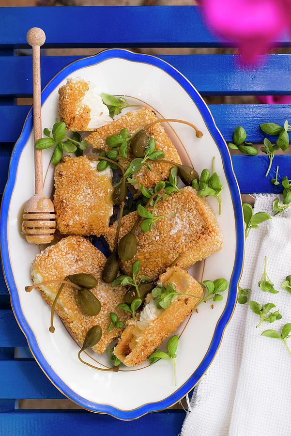Fried Feta Cheese In A Sesame Seed Coating With Honey, Caper Fruits And Basil Photograph by Great Stock!