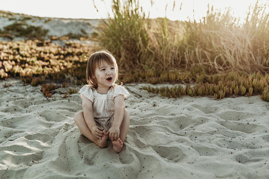 Sunset Photograph - Front View Of Young Toddler Girl Looking Away And Laughing At Beach by Cavan Images