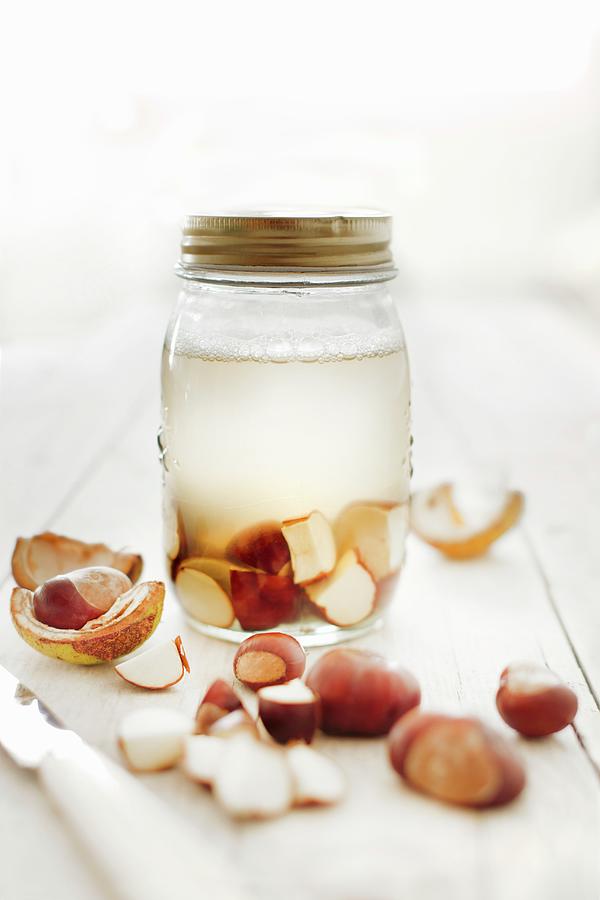 Frothy Water And Freshly Cut Chestnuts In A Screw Top Glass Jar Photograph by Sabine Lscher