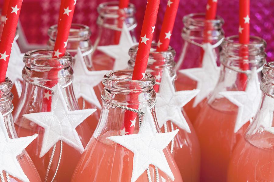Fruit Juice In Glass Bottles Decorated With White Stars Photograph by Karl Stanzel