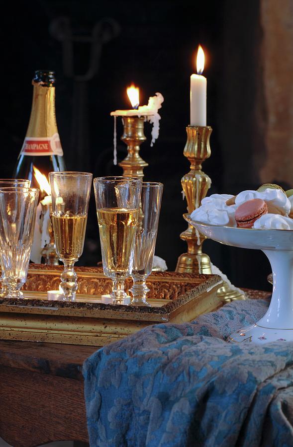 Full Champagne Glasses On Tray In Front Of Lit Candles In Brass Candlesticks And China Dish Of Confectionery On Tablecloth Photograph by Christophe Madamour