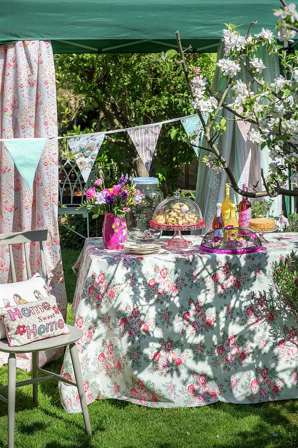 Garden Buffet In Sunshine On Floral Tablecloth Below Pavilion Decorated With Bunting Photograph by Winfried Heinze