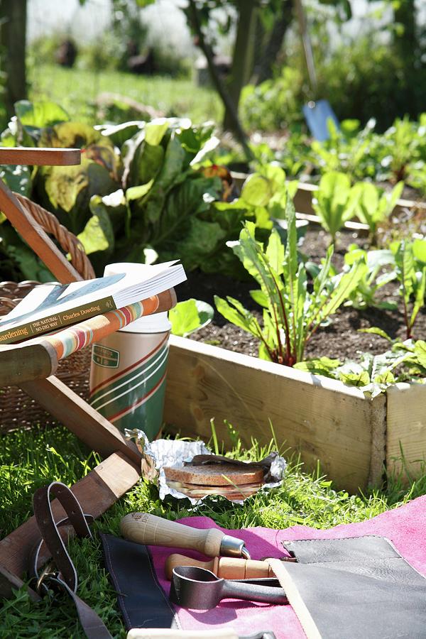 Garden Tools And A Garden Chair Next To A Raised Vegetable Plot With A Wooden Surround Photograph by Simon Scarboro