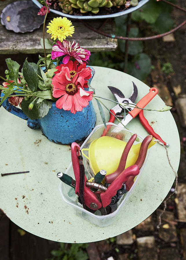 Gardening Tools And Jug Of Flowers On Garden Table Photograph by Alexander Van Berge