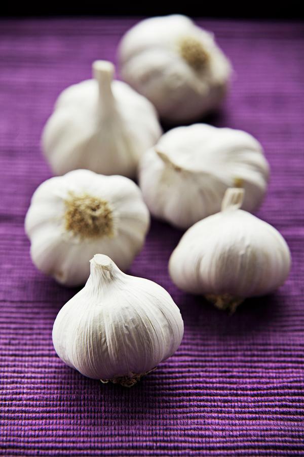 Garlic Bulbs On A Purple Surface Photograph by Richard Church