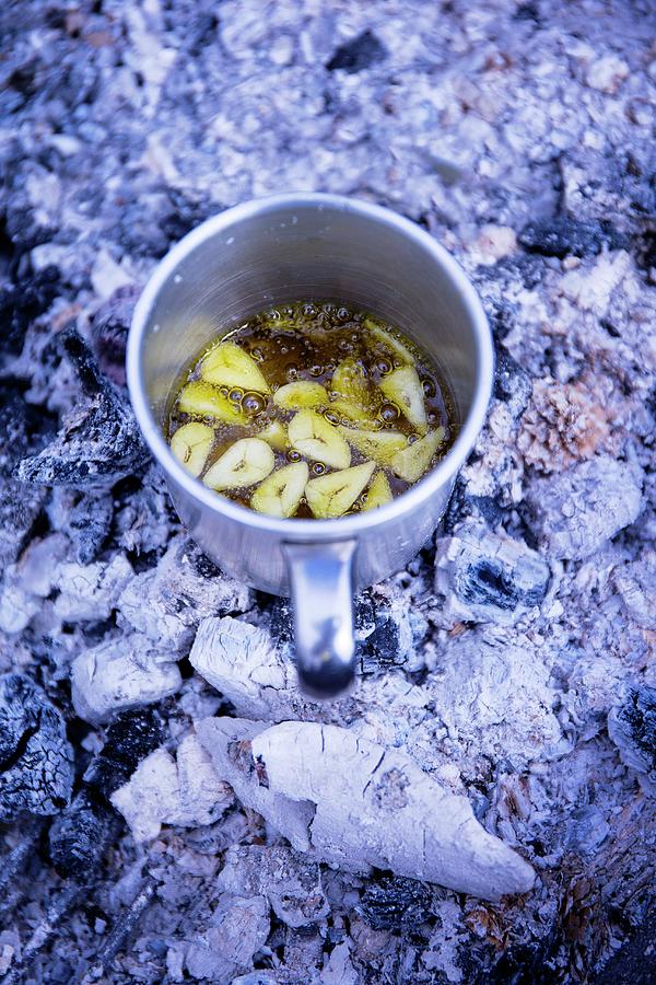 Garlic Flavoured Olive Oil In A Tin Mug Photograph by Nicolas Lemonnier