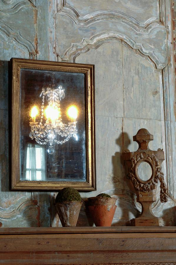 Gilt-framed Mirror On Faded Wood-panelled Wall And Terracotta Pots Next To Wooden Sculpture On Table Top Photograph by Christophe Madamour